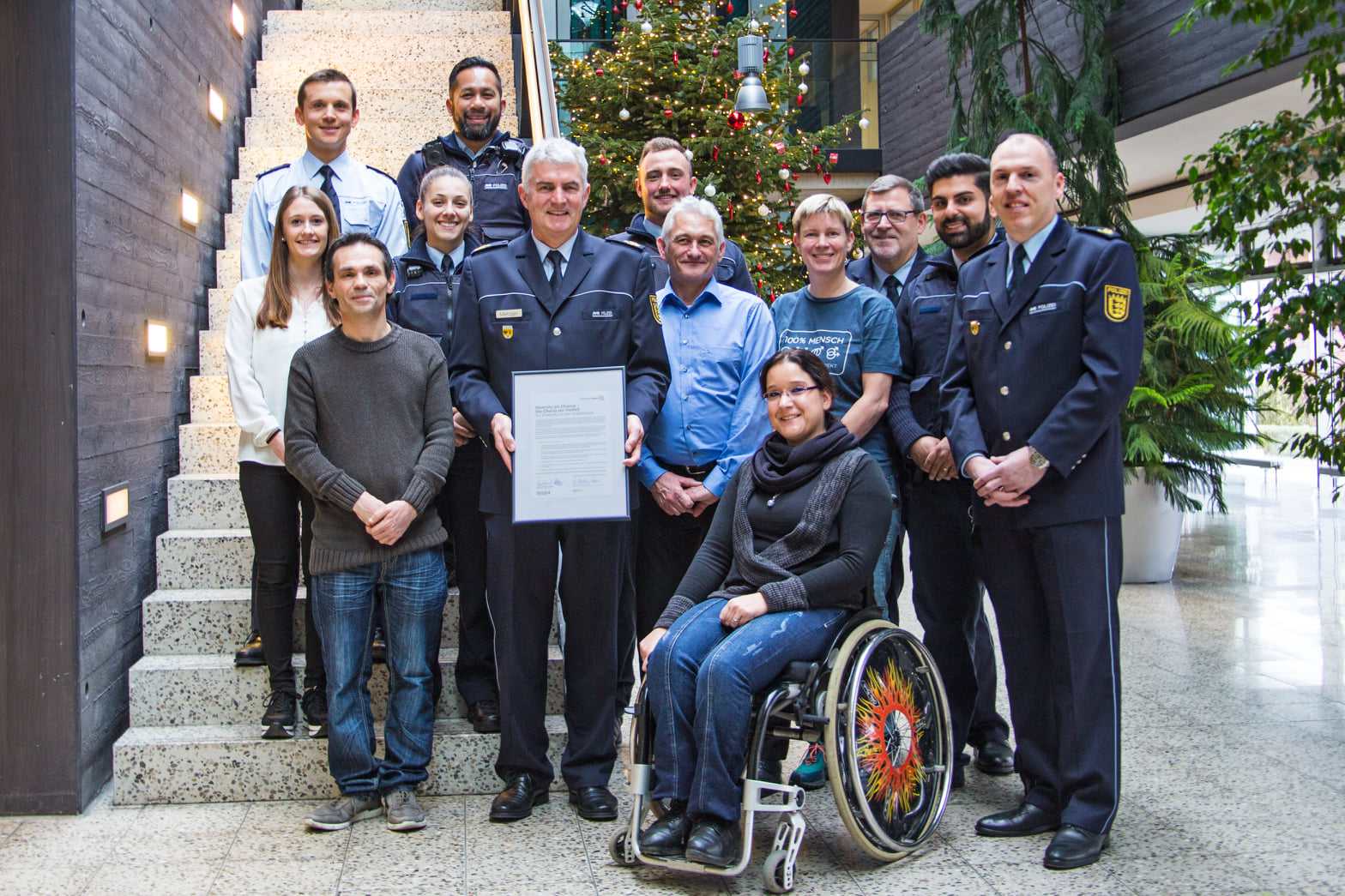 Angehörige des Polizeipräsidiums im Eingangsbereich. Im Rollstuhl, jung, alt, mit Behinderung,...